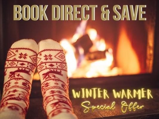 Gorse Hill Winter Warmer Offer image featuring a person warming their feet by a roaring fire