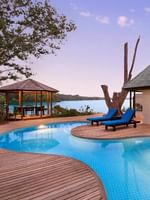 Efate Pool Villa featuring curved infinity pool and wooden deck with blue loungers at twilight at warwick le lagon-vanuatu 