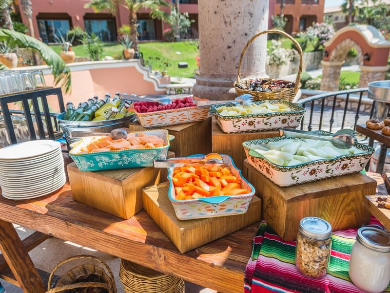 Colorful fresh fruit like watermelon, cantaloupe, and papaya on a wooden brunch buffet table at Hacienda Del Mar Los Cabos