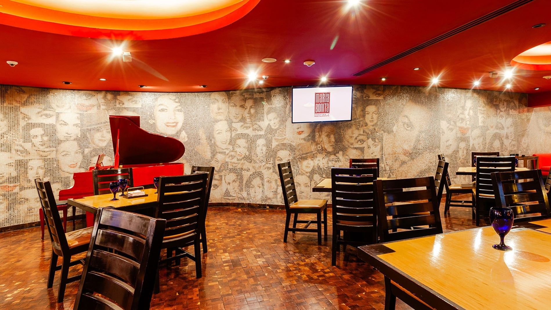 Maria Bonita restaurant featuring a red piano and a wall of black and white icons at Camino Real Guadalajara