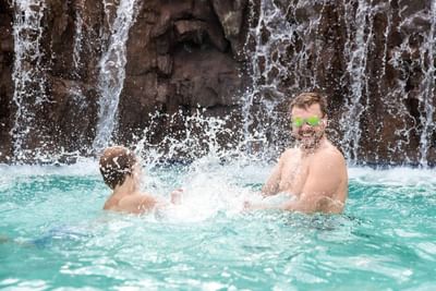 Dad and son playing in swimming pool splashing