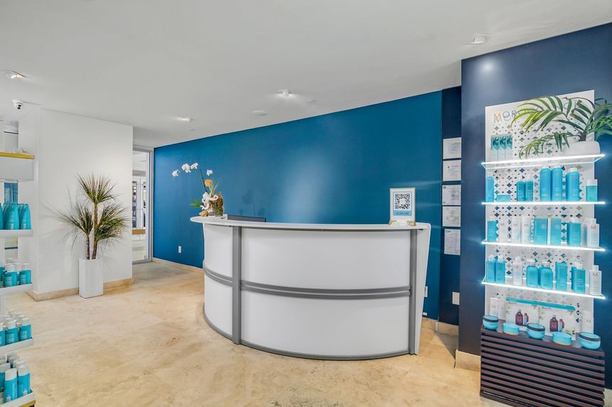 White curved reception desk and blue accent wall with product display at The Atlantic Hotel & Spa