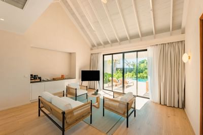 Modern living room in the 2-Bedroom Beach Villas at Ananea Madivaru Maldives, with rattan chairs and poolside patio access