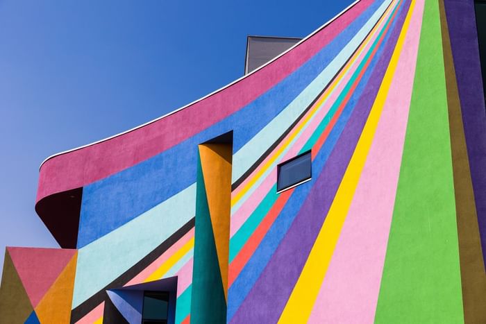 Towner Eastbourne Exterior. A vibrantly painted building with geometric patterns and stripes under a clear blue sky.