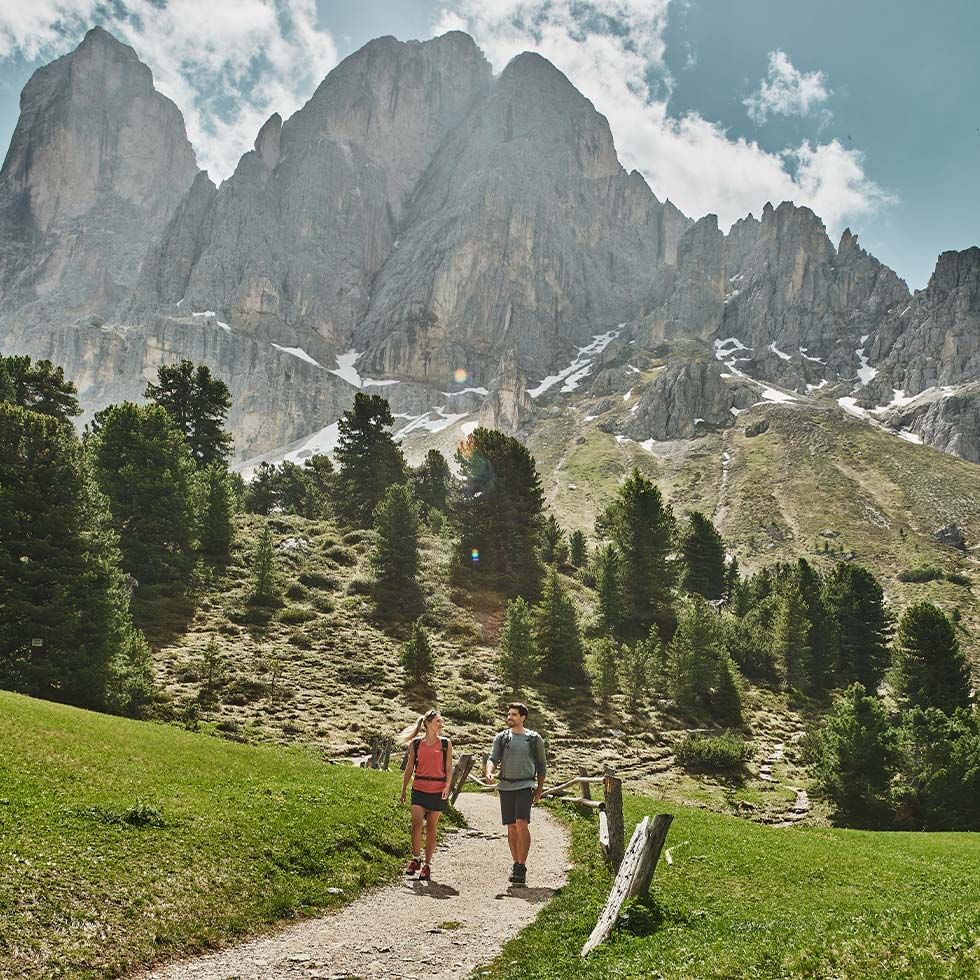 Coppia in montagna su sentiero con montagne e neve sullo sfondo per KRONPLATZ SUMMER EXPERIENCE