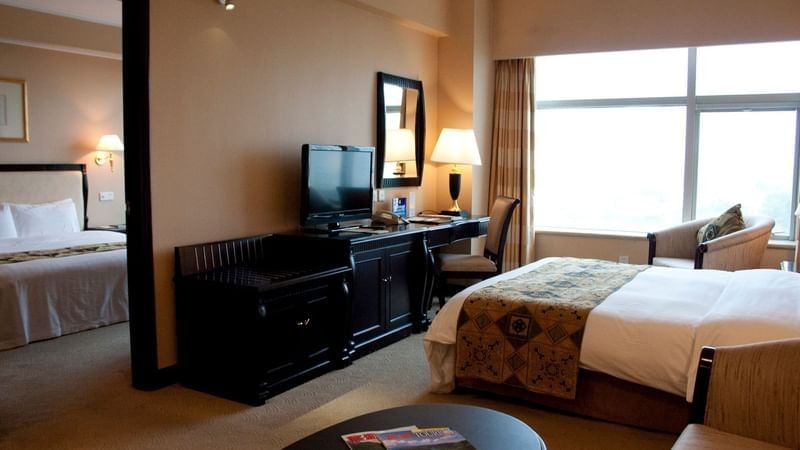 TV facing a bed with a work desk by the window in Family Suite Celebrity 2 at Celebrity International Grand Hotel