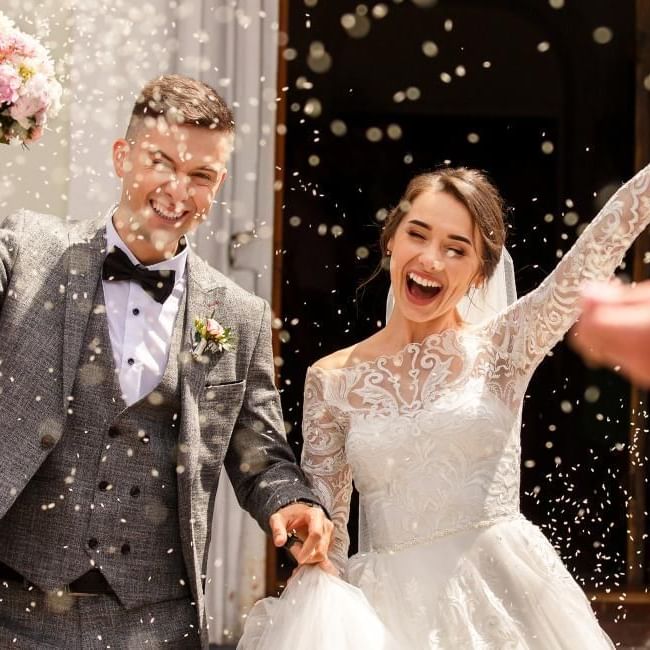 Just married couple with rice being thrown at them featuring our article on 