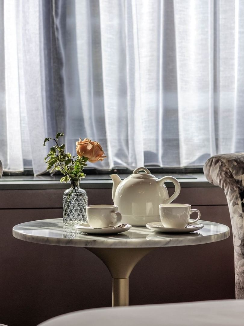 Two armchairs & a tea table with a rose and teapot in an Executive Room at The Capital Hotel, Apartments & Townhouse