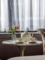 Two armchairs & a tea table with a rose and teapot in an Executive Room at The Capital Hotel, Apartments & Townhouse