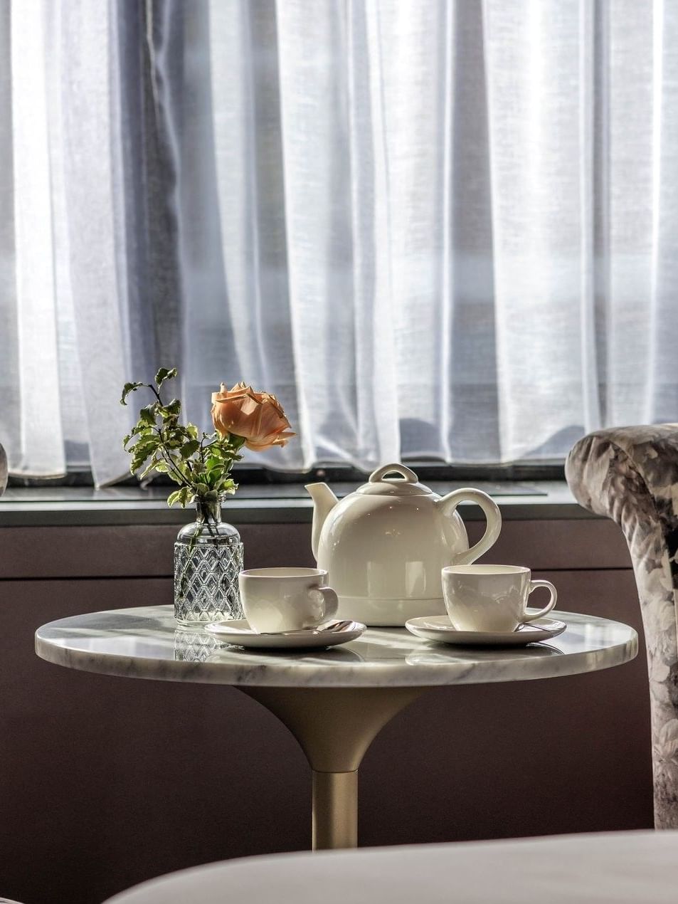 Two armchairs & a tea table with a rose and teapot in an Executive Room at The Capital Hotel, Apartments & Townhouse