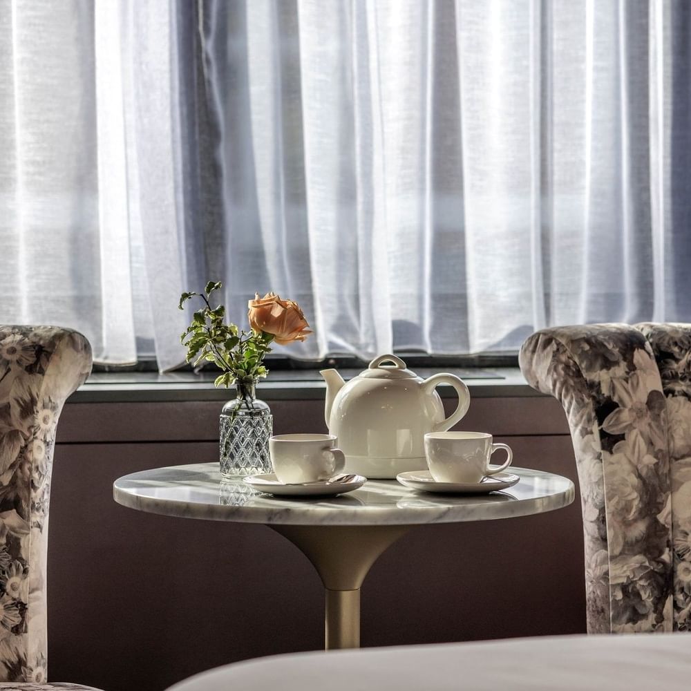 Two armchairs & a tea table with a rose and teapot in an Executive Room at The Capital Hotel, Apartments & Townhouse