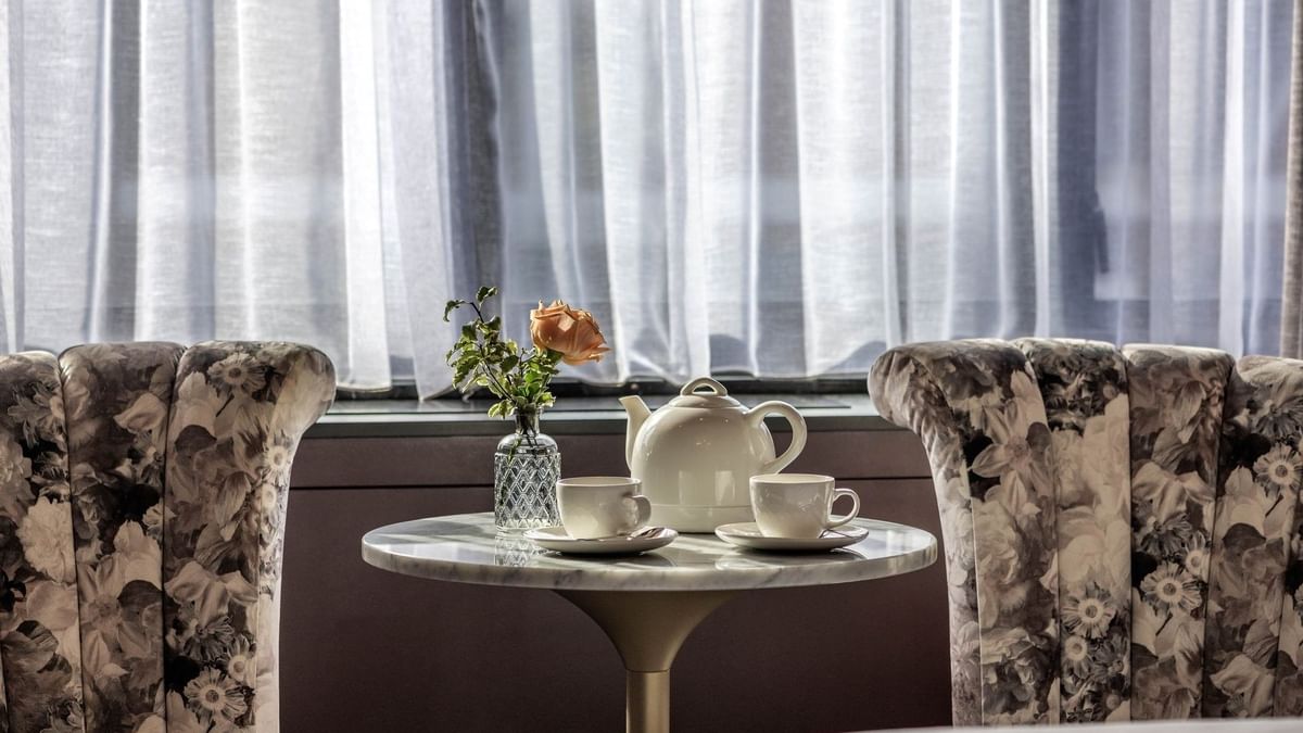Two armchairs & a tea table with a rose and teapot in an Executive Room at The Capital Hotel, Apartments & Townhouse