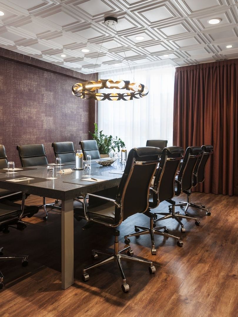 Boardroom table set-up under a circular pendant light in Salon Du Président at Warwick Le Crystal Montreal