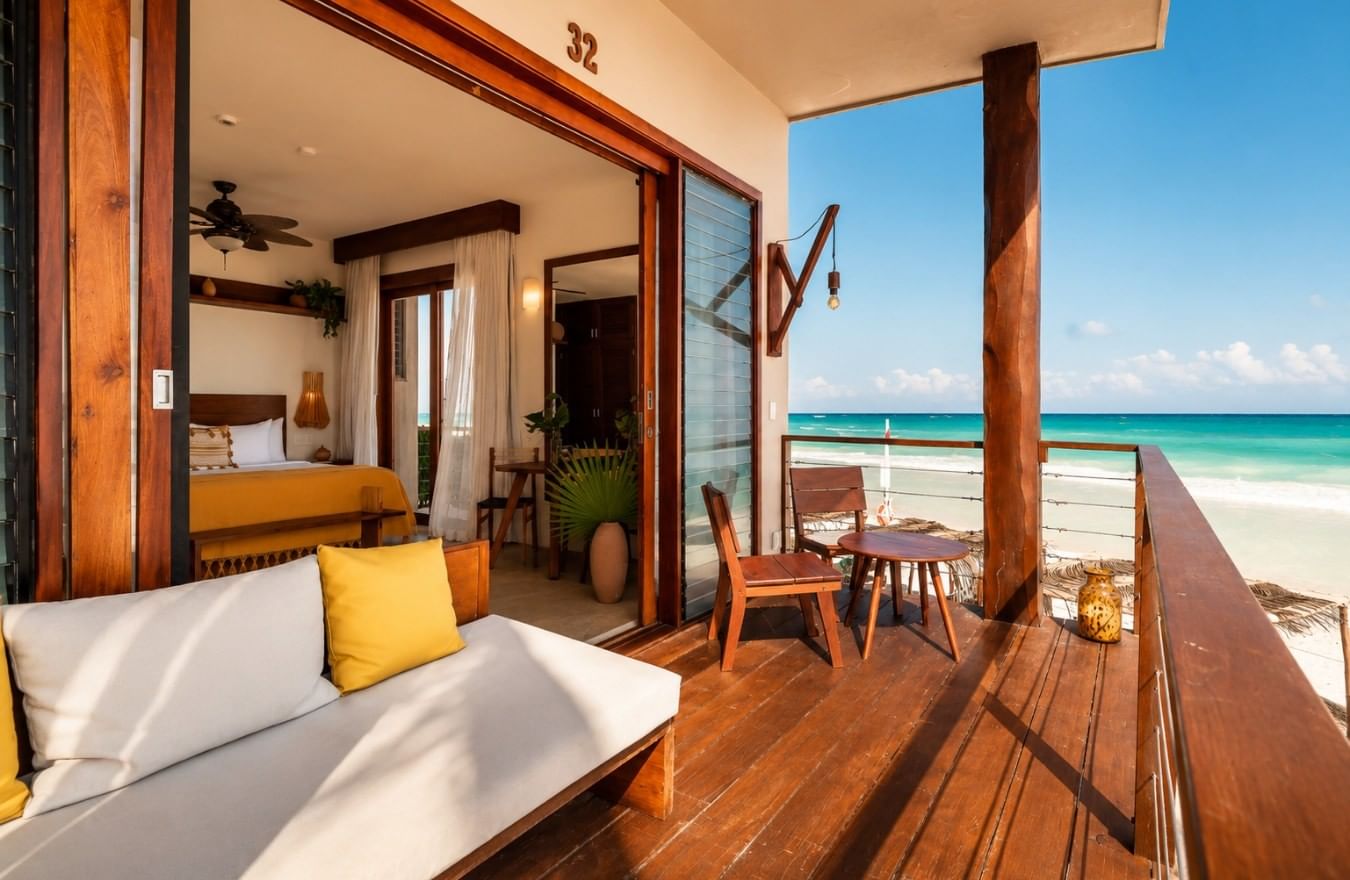 A La Zebra beachfront room opening onto a furnished wooden terrace overlooking the Caribbean in Tulum, Mexico.