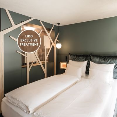 Green-themed hotel room with two beds, nightstand, hanging lamps, and 