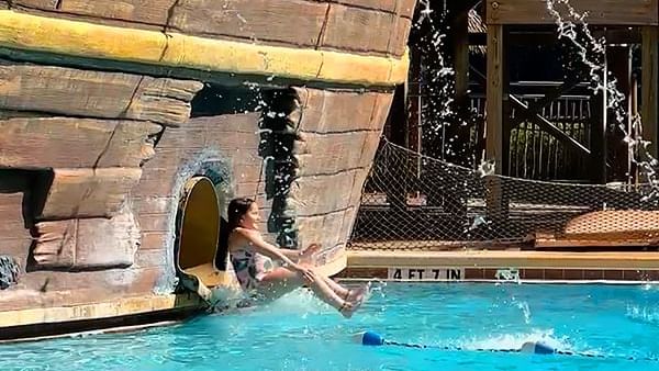 Lady sliding out of Pirates Plunge Slide into pool at Lake Buena Vista Resort Village & Spa