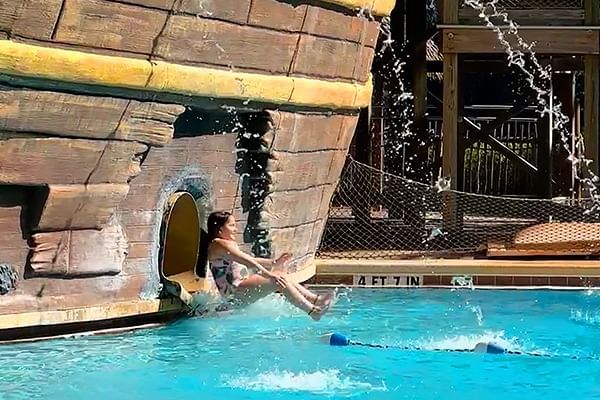 Lady sliding out of Pirates Plunge Slide into pool at Lake Buena Vista Resort Village & Spa