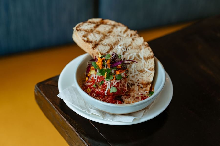 Grilled bread accompanies a bowl of tomato-based dish garnished with cheese and microgreens at Warwick Denver