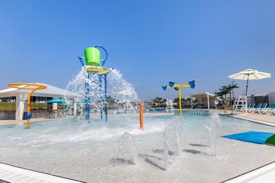 Kiddie Pool with tipping bucket, splash pads, and fountains under a blue sky at Off Shore Resort