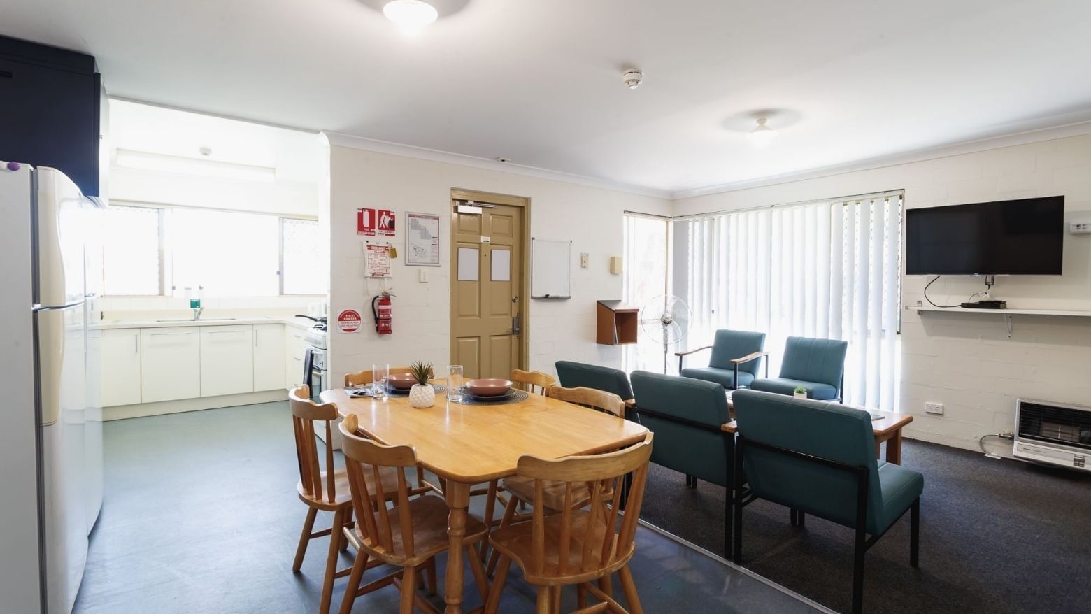A communal kitchen and dining area with a table, chairs, and appliances at Vickery House.