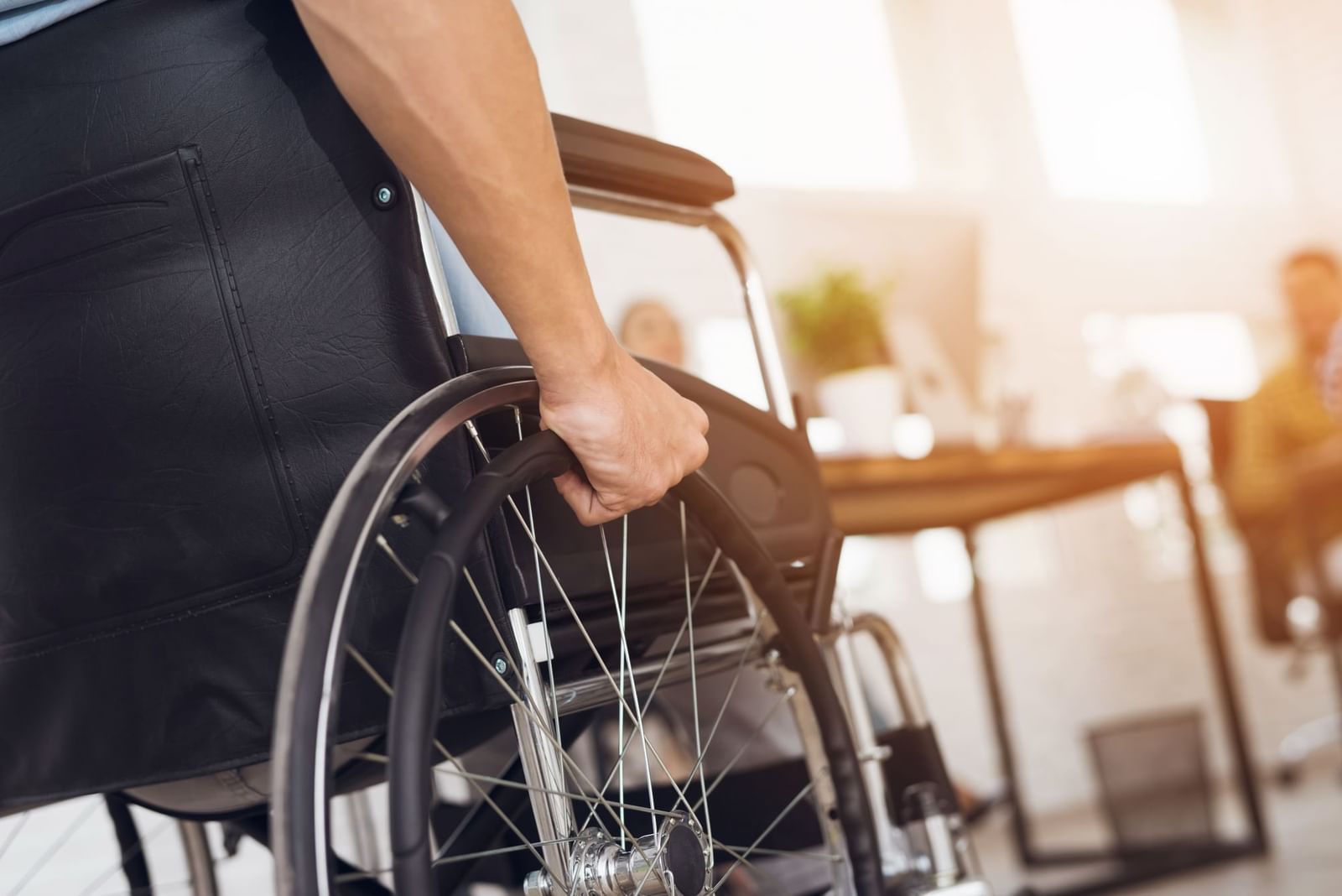 Close-up of a hand gripping the wheel of a black wheelchair at Pullman Sydney Olympic Park