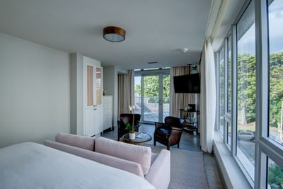 room with one bed, love seat and chairs with floor to ceiling wi