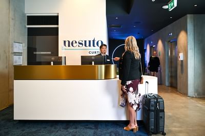 Guest checking in by the reception at Nesuto Curtin Perth Hotel