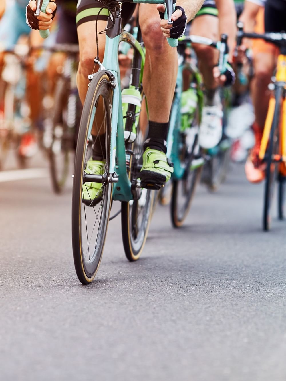 Professional cyclists racing on road bikes during a competitive cycling event with colorful jerseys and equipment