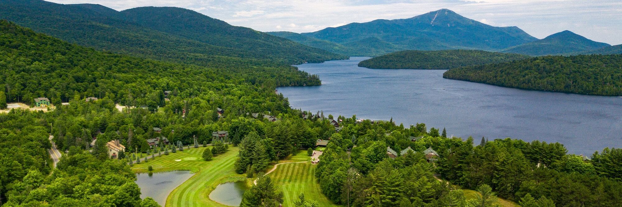 Aerial view of golf course, body of water, and mountains