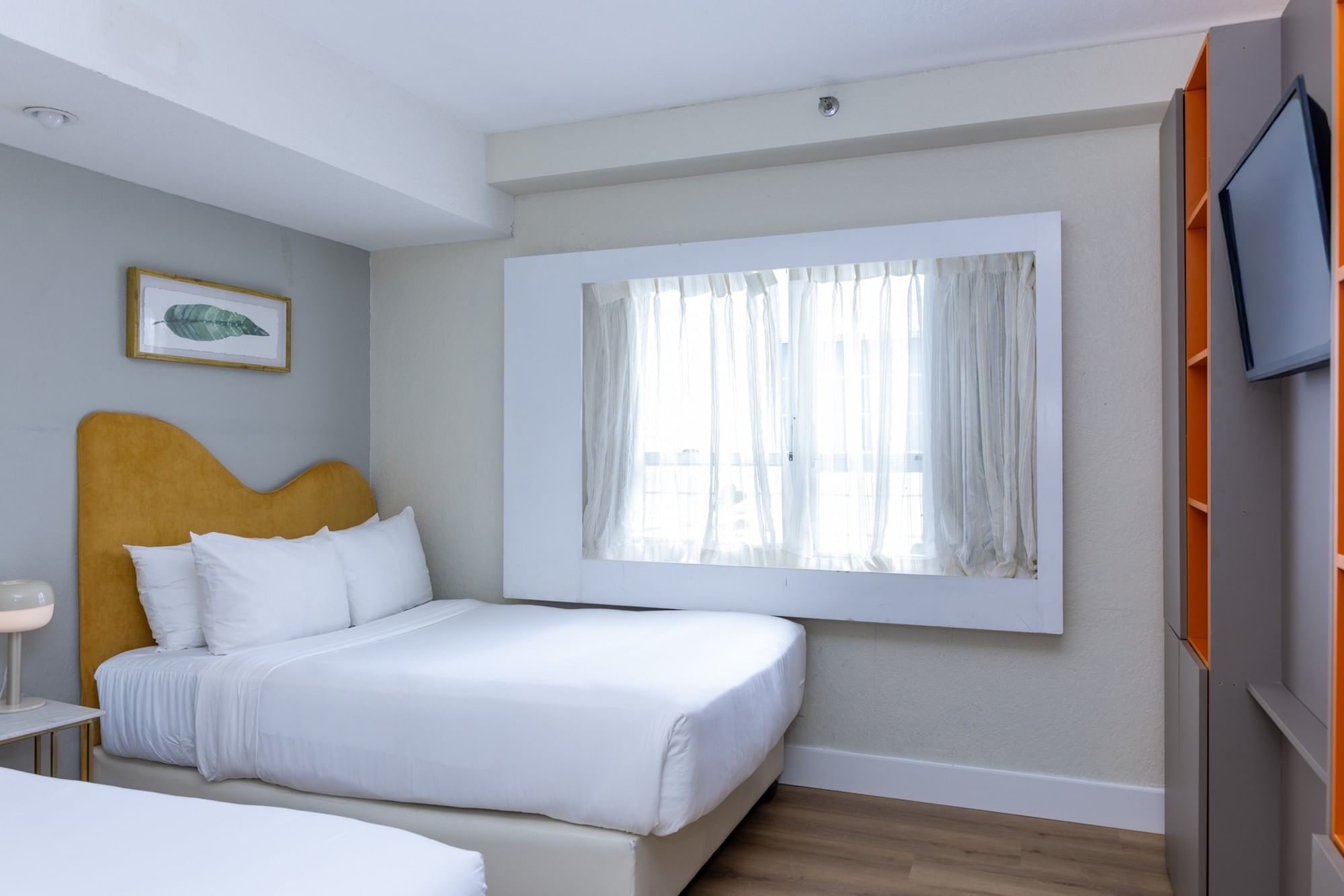 A hotel room with a bed, window, and TV