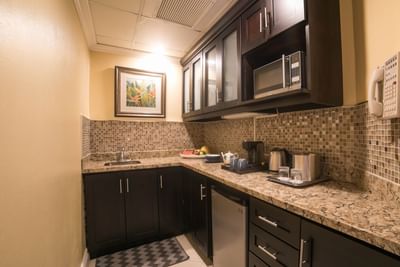 A modern kitchenette with countertops and elegant cabinets in the Presidential Suite at Courtleigh Hotel & Suites