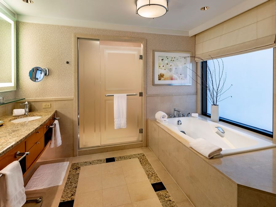 Luxury bathroom bathtub by the vanity with smoked glass doors in Studio Suite at The Umstead Hotel and Spa