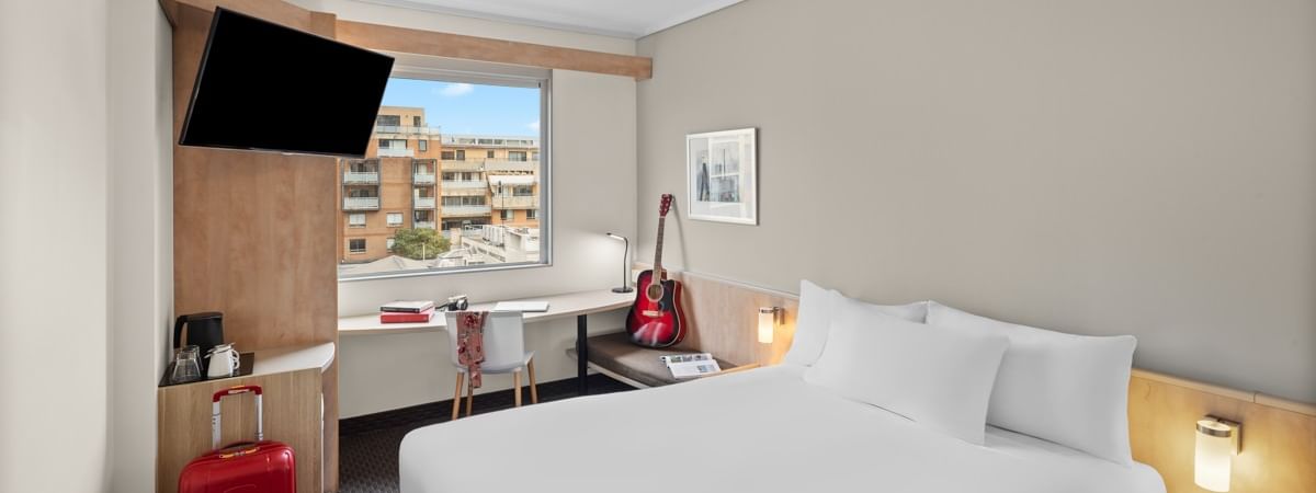 Standard room with one queen bed, work desk, wall-mounted TV, and city view at Ibis Sydney Darling Harbour in Pyrmont