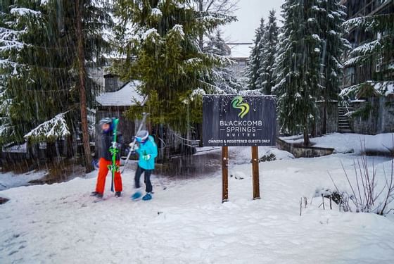 Kids playing in the snow by the hotel signage board at Blackcomb Springs Suites