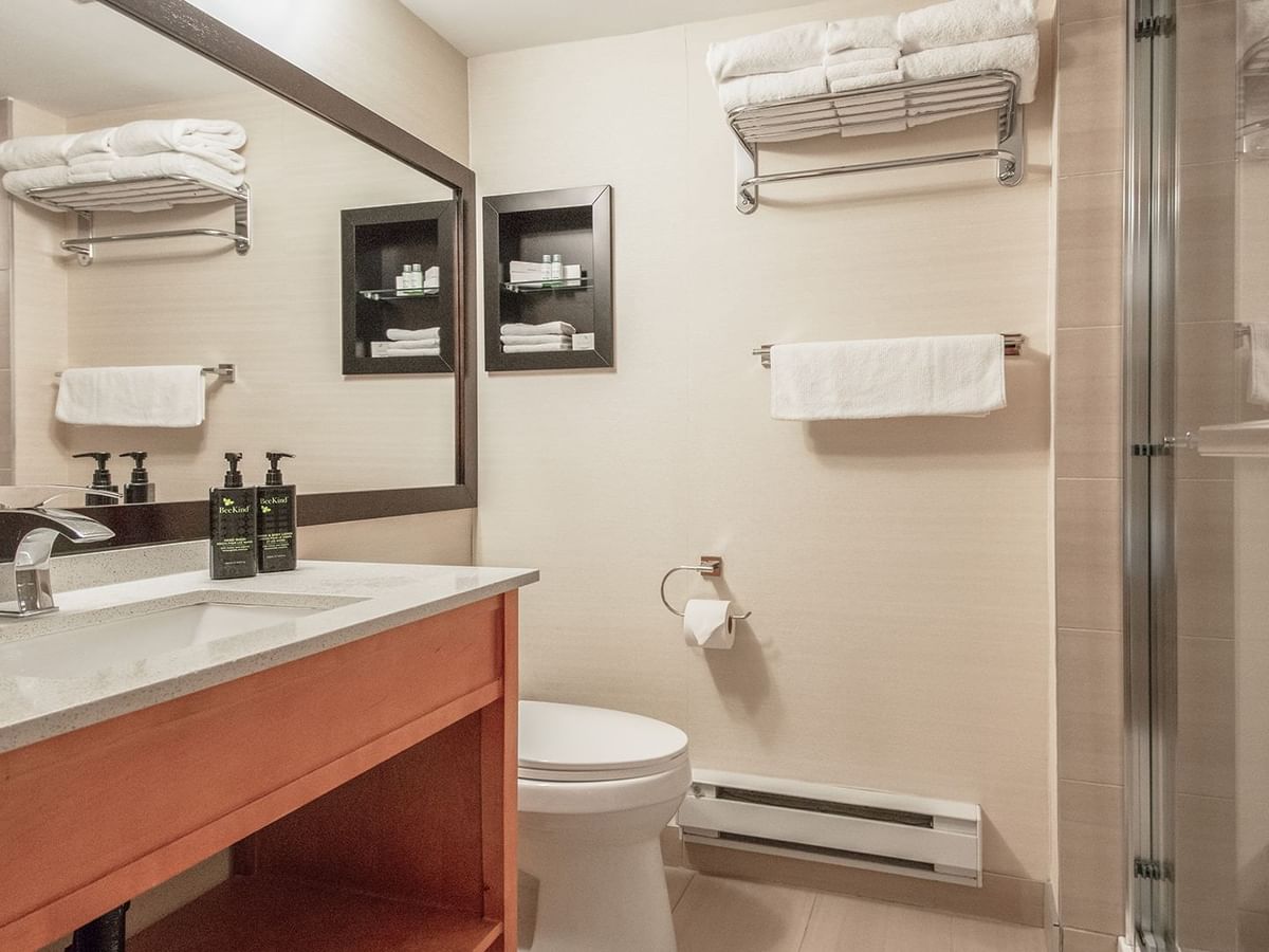 Hotel bathroom with toilet, shower, sink, soap and towels