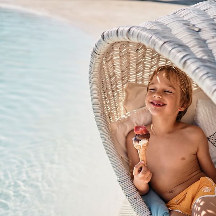 A kid enjoying ice cream at the beach near Falkensteiner Hotels