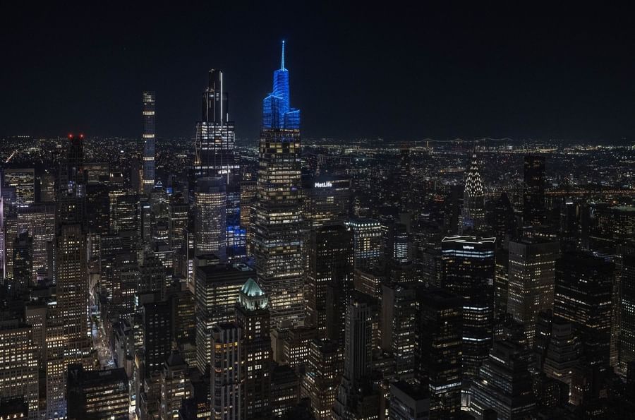 Nighttime cityscape with illuminated skyscrapers and a prominent blue-lit tower.