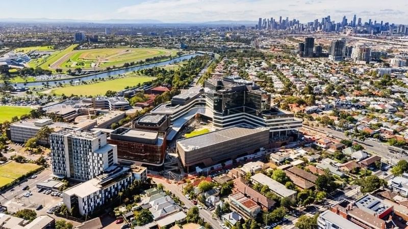 Aerial view of Footscray with modern buildings, a river, and the Melbourne CBD skyline in the distance.