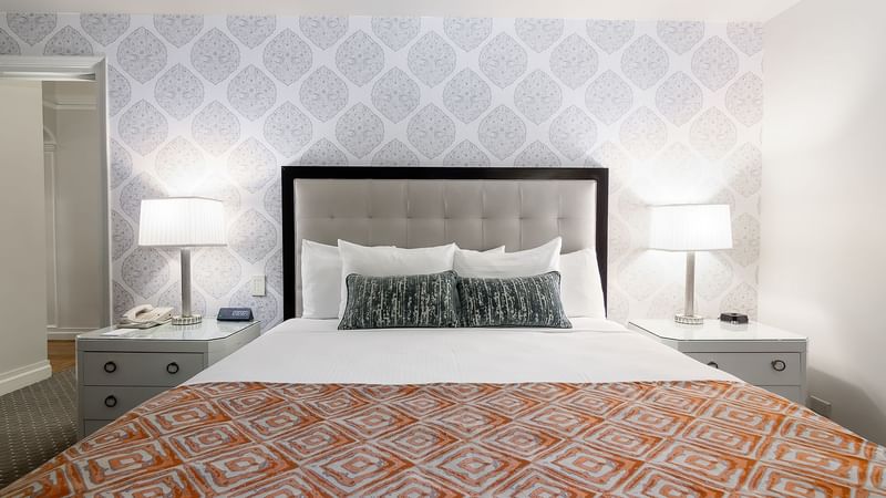 Bedside cupboards by the bed with a cushioned headboard in Premier Suite at Warwick New York