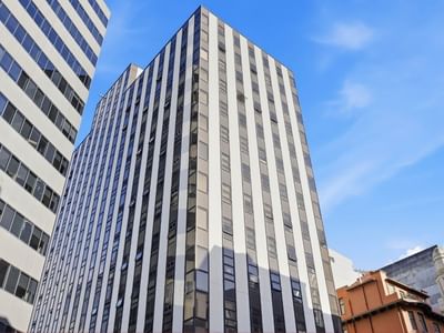 Tall modern building with glass windows against clear blue sky at UniLodge Stafford House.