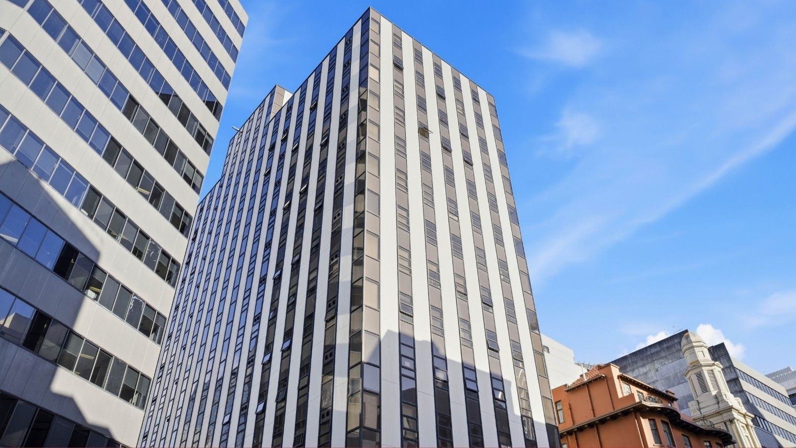 Tall modern building with glass windows against clear blue sky at UniLodge Stafford House.