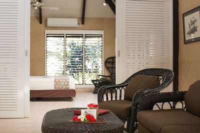 Lagoon Bures room interior with wicker chairs, coffee table, bed, and warm lighting at Musket Cove Island Resort & Marina