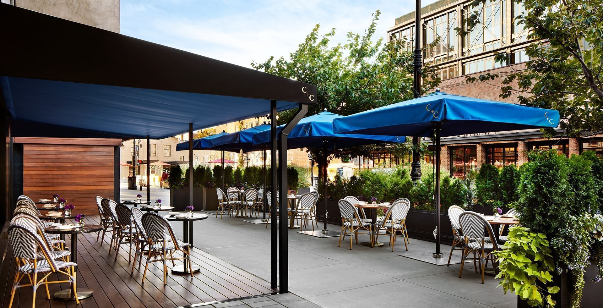 Coffee and cocktails cafe outdoor patio with blue umbrellas and chairs at Gansevoort Meatpacking NYC