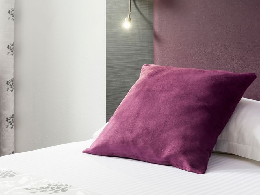 Close up on a purple color pillow in a bed at City Hotel