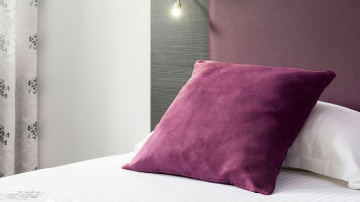 Close up on a purple color pillow in a bed at City Hotel