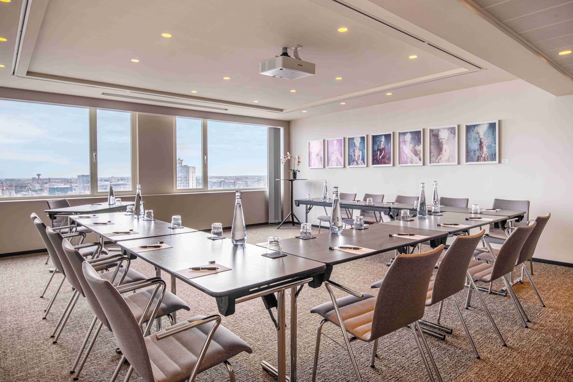 Modern meeting room with city view, C-shape table & leather chairs at The Hotels Brussels