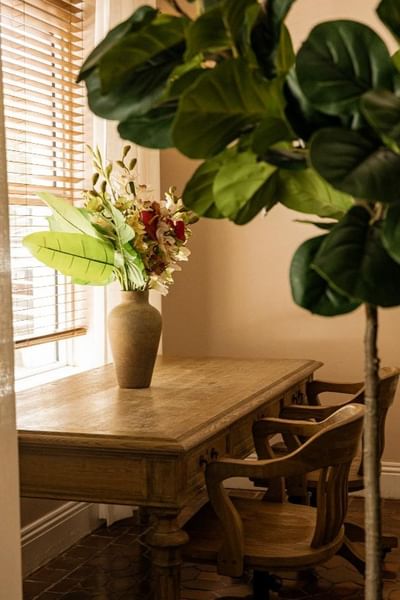 Wooden table with a flower arrangement and two chairs under a window at Clinton Hotel and Spa