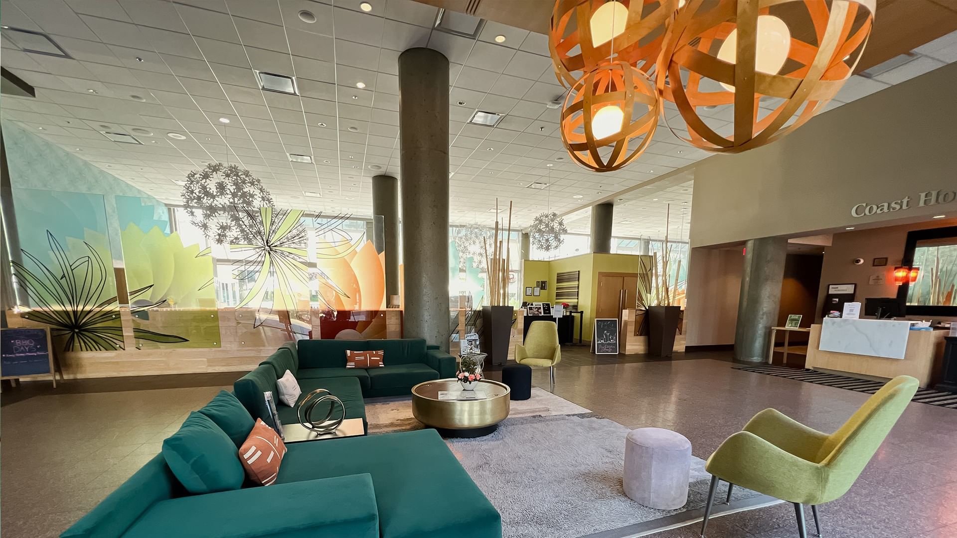 A spacious hotel lobby with a seating area, a reception desk, and modern lighting fixtures.