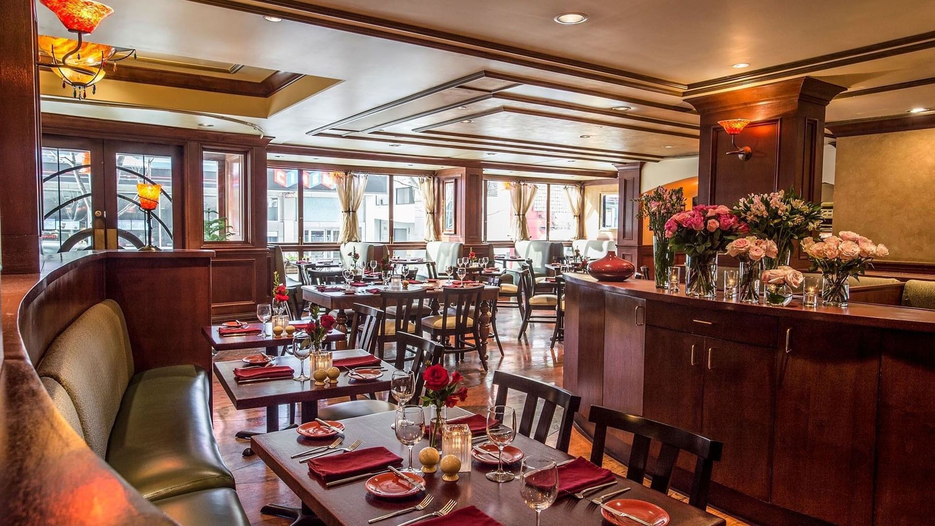 Margaux Lounge featuring set tables and vases of roses by a long wooden bar at Warwick Seattle