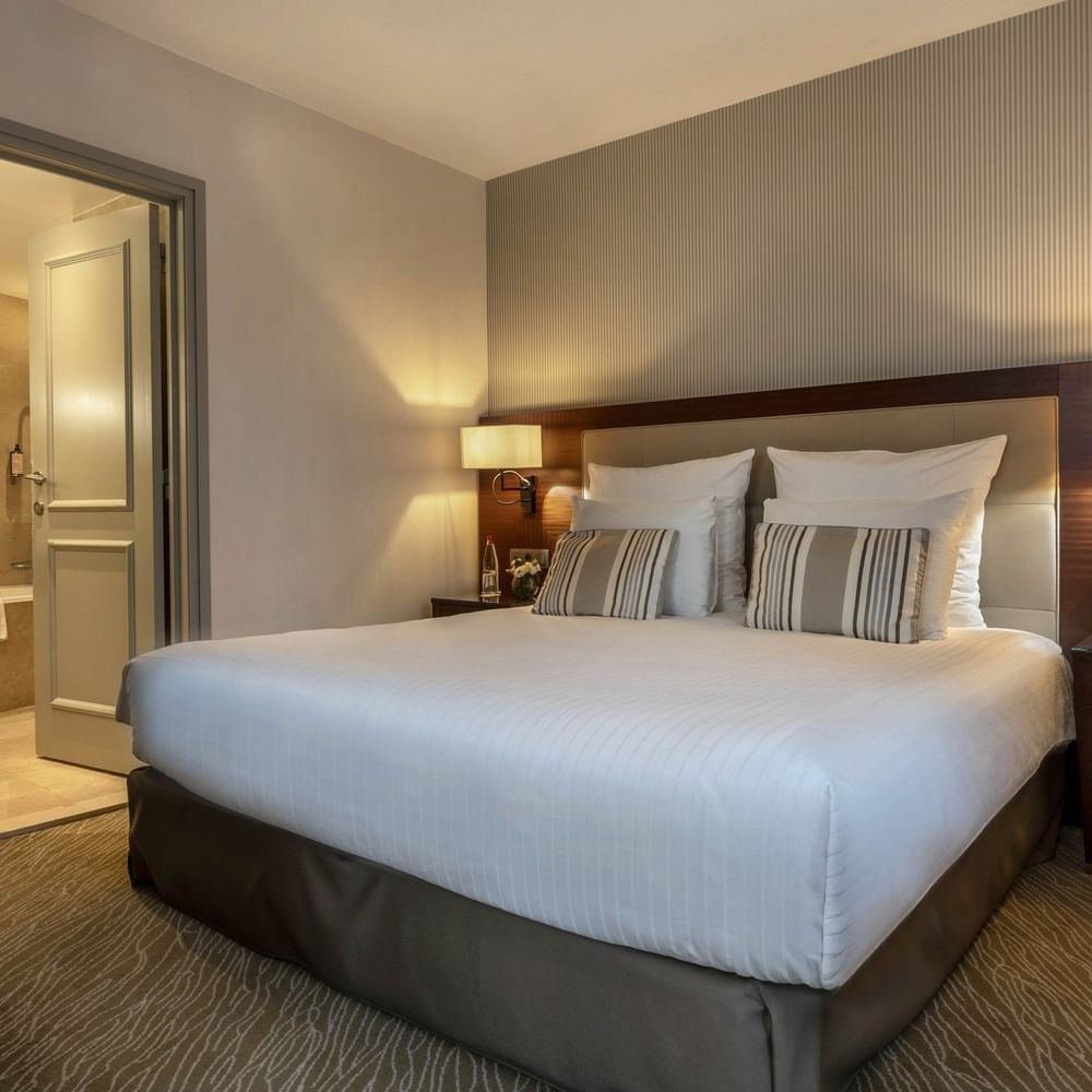 Bed between the side tables near the doorway to the bathroom in Junior Suite Privilege View at Warwick Grand Place Brussels